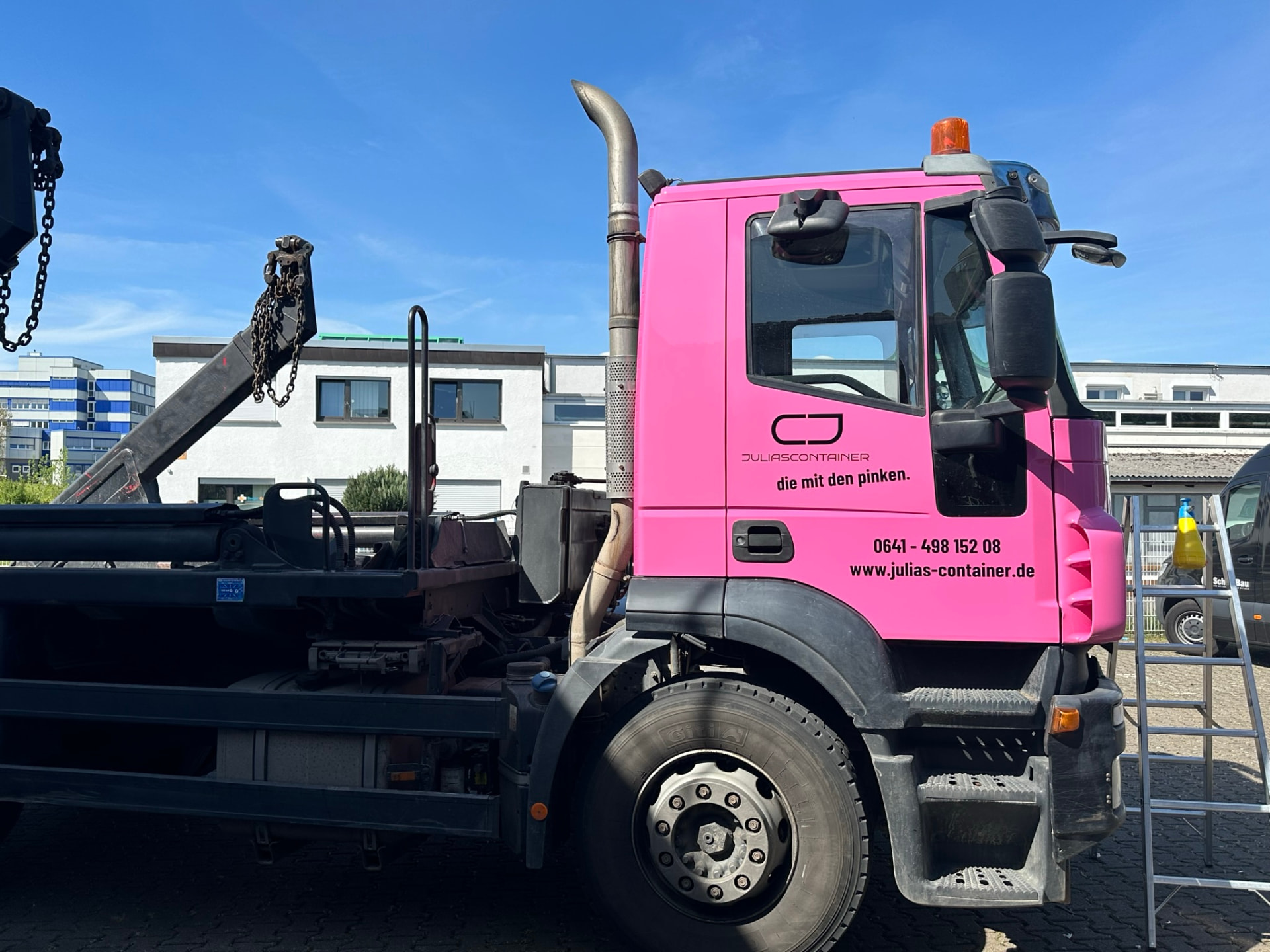 Rosa LKW von Julias Container mit Logo und Kontaktdaten